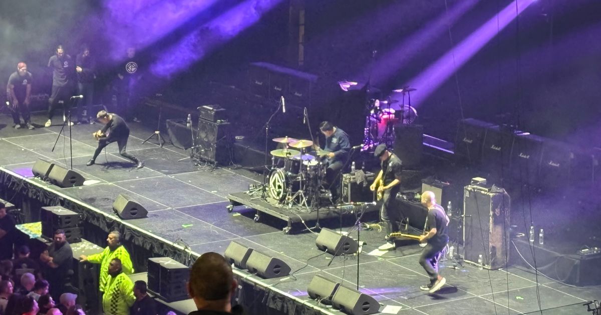 Cadena Perpetua onstage at Movistar Arena under purple lights, a guitarist leaning forward at the edge of the stage